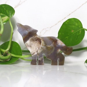 Könnte beinhalten: Eine geschnitzte Agat-Wolf-Figur in braunen, weißen und violetten Farbtönen. Der Wolf heult mit offenem Maul und zurückgeneigtem Kopf. Der Agat ist durchscheinend und hat eine kristalline Textur.