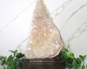 May include: A large, white, crystal cluster on a wooden base. The crystal is a cluster of many small, clear crystals.