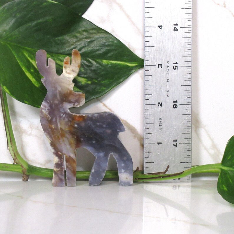 May include: A decorative deer figurine made of agate, with brown, white, and gray colors. The deer is standing on a white surface and is approximately 5 inches tall.