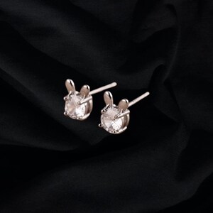 May include: A pair of silver stud earrings with clear crystal stones shaped like bunny rabbits.