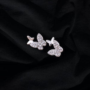 May include: A pair of silver butterfly earrings with clear crystal accents.