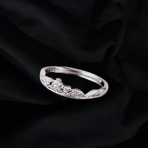 May include: A silver ring with a crown design featuring small clear stones.