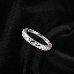 May include: A silver ring with a geometric pattern on the band.