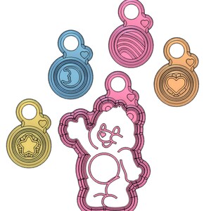 May include: Five cookie cutters, one shaped like a bear, and four shaped like circles with different designs. The bear cookie cutter is pink, the circle cookie cutters are blue, pink, and yellow.