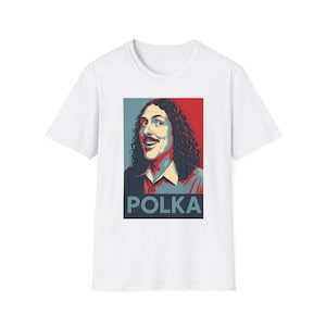May include: White t-shirt featuring a portrait of a man with curly hair and a mustache, set against a red and blue background. The word "POLKA" is printed in a dark blue font at the bottom of the image. The shirt is a crew neck.