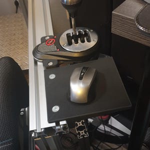 May include: A black metal gear shifter with a silver knob and a black mouse pad with a silver mouse on top. The gear shifter is mounted on a silver metal frame.