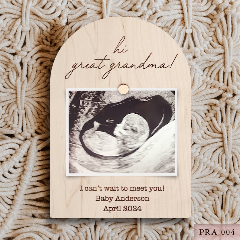 May include: A wooden plaque with an arched top, featuring the text "hi great grandma!" and a sonogram image. Below the image, it reads "I can't wait to meet you! Baby Anderson April 2024."