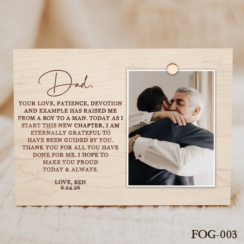 Puede incluir: Una placa de madera con una foto de un padre y un hijo abraz&aacute;ndose. La placa tiene un mensaje grabado que dice: "Pap&aacute;. Tu amor, paciencia, devoci&oacute;n y ejemplo me han hecho crecer de un ni&ntilde;o a un hombre. Hoy, al comenzar este nuevo cap&iacute;tulo, estoy eternamente agradecido por haber sido guiado por ti. Gracias por todo lo que has hecho por m&iacute;. Espero hacerte sentir orgulloso hoy y siempre. Con amor, Ben 6.24.26"