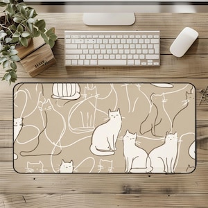 May include: A rectangular desk mat featuring a repeating pattern of white cats on a tan background. The cats are depicted in various poses with a minimalist line art style. The mat has a black border and is designed for use with a computer setup.