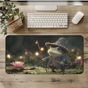 May include: A rectangular desk mat featuring a whimsical illustration of a frog dressed as a wizard. The frog wears a blue hat and coat, holding a staff with a glowing light. A pink lotus flower and bokeh lights are in the background.