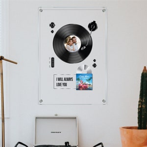May include: A black and white photo of a couple is displayed on a record player with a vinyl record and a silver CD. The record player is framed in a clear acrylic frame with the text "I will always love you".