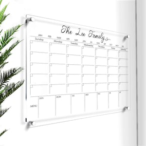 May include: A clear acrylic dry erase calendar with a black frame and black text. The calendar is labeled with the months of the year and days of the week. The top of the calendar says "The Lee Family".