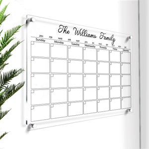May include: A clear acrylic dry-erase calendar with a black frame and black text. The calendar is labelled with the months of the year and days of the week. The text at the top reads "The Williams Family".
