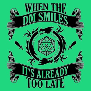 Op de afbeelding: Een felgroen grafisch ontwerp met een zwarte 20-zijdige dobbelsteen in een cirkelvormig drakenmotief. De tekst luidt bovenaan WHEN THE DM SMILES en onderaan IT'S ALREADY TOO LATE, geflankeerd door twee kleine zwarte zwaardpictogrammen.