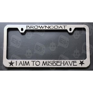 May include: A silver license plate frame with the text "BROWNCOAT I AIM TO MISBEHAVE" in black lettering.