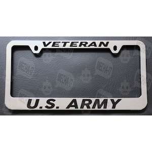 May include: A silver metal license plate frame with black lettering that reads "Veteran" and "U.S. Army".