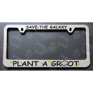May include: Silver license plate frame with the text "Save the Galaxy Plant a Groot" in black lettering with green leaves and a small green Groot character.