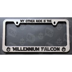 May include: A silver metal license plate frame with the text "My other ride is the Millennium Falcon" and a black and white image of the Millennium Falcon on each side.