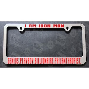 May include: A silver metal license plate frame with red text that reads "I AM IRON MAN GENIUS.PLAYBOY.BILLIONAIRE.PHILANTHROPIST."