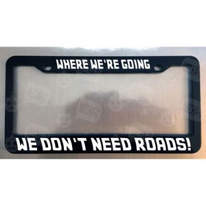 Where We're Going We Don't Need Roads Glossy Black License Plate Frame White letters
