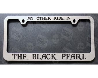 May include: Silver license plate frame with the text "My other ride is The Black Pearl" in black lettering.