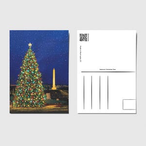 May include: A postcard featuring a brightly lit Christmas tree with a star on top, set against a dark blue starry sky. The Washington Monument is visible in the background. The back of the postcard is blank with lines for writing.