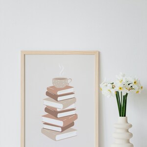 May include: A framed print of a stack of books with a steaming cup of coffee on top. The books are in shades of brown and beige, and the coffee cup is a light brown with a speckled pattern. The background is a light beige.