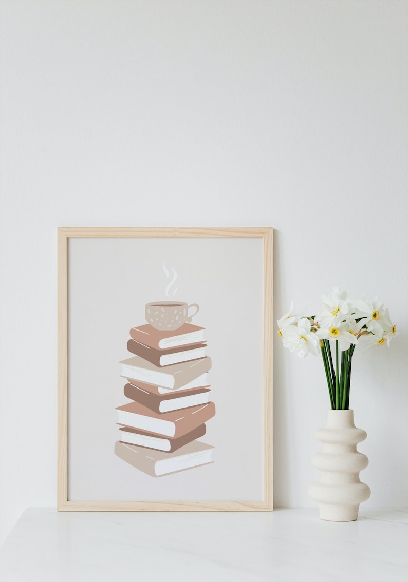 May include: A framed print of a stack of books with a steaming cup of coffee on top. The books are in shades of brown and beige, and the coffee cup is a light brown with a speckled pattern. The background is a light beige.