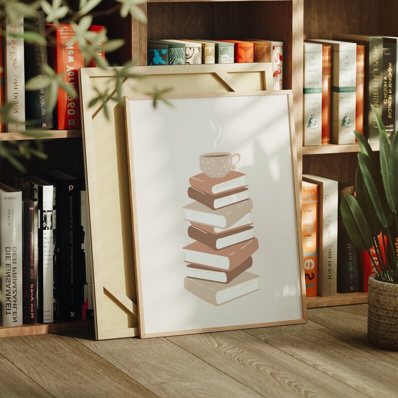 May include: A framed print with a stack of books and a coffee cup on top. The books are in shades of brown and beige, and the coffee cup is white with a brown design. The print is on a white background and has a wooden frame.