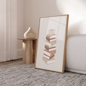 May include: A framed print with a beige background featuring a stack of six books with a steaming cup of coffee on top. The books are in shades of brown and beige.
