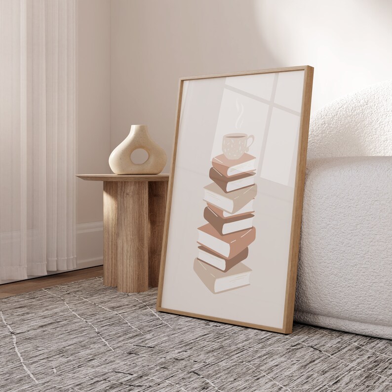 May include: A framed print with a beige background featuring a stack of six books with a steaming cup of coffee on top. The books are in shades of brown and beige.