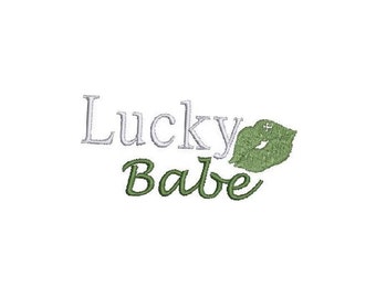 Peut inclure: Texte blanc qui dit "Lucky Babe" avec une empreinte de lèvres verte à droite du texte.