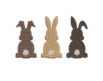 Peut inclure: Trois lapins brodés, en brun, beige et gris, avec des queues blanches, dos au spectateur.
