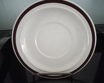 May include: White saucer with a brown band around the edge.