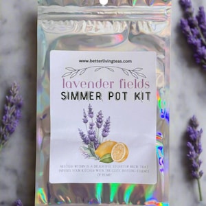 May include: A silver iridescent pouch with a white label that reads "www.betterlivingteas.com lavender fields SIMMER POT KIT NESTLED WITHIN IS A DELIGHTFUL STOVETOP BREW THAT INFUSES YOUR KITCHEN WITH THE COZY, INVITING ESSENCE OF HOME". The label features a watercolor illustration of lavender flowers and lemons.