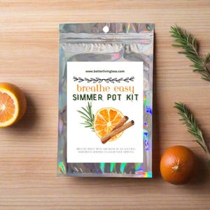 May include: A silver foil pouch with a white label that reads "breathe easy SIMMER POT KIT" and features a watercolor illustration of an orange slice, cinnamon sticks, and rosemary. The text "www.betterlivingteas.com" is printed at the top of the label. The label also includes the text "breathe freely with this blend of all natural ingredients designed to clear your airways."