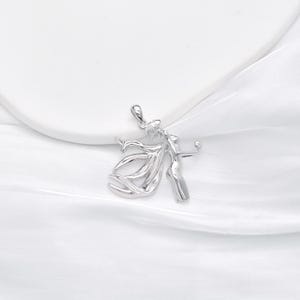 May include: Silver pendant featuring a stylized design of two figures dancing together.