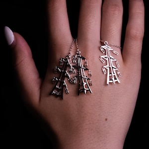 May include: A set of silver-toned jewelry consisting of two dangling charms shaped like electrical transmission towers and a matching ring featuring a single electrical tower design, all crafted with intricate metal lattice detailing.