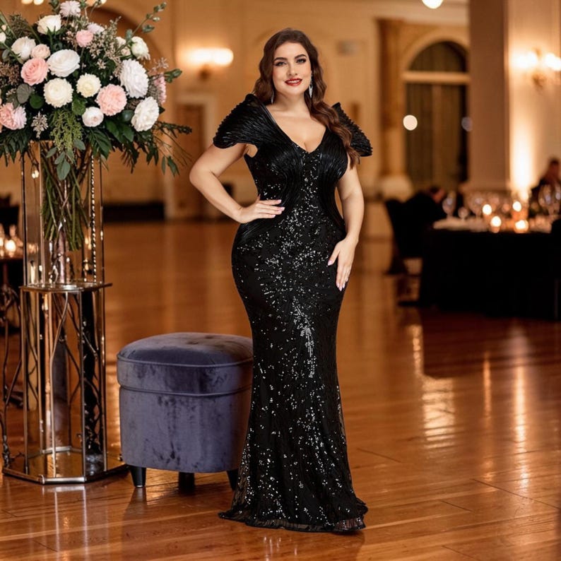 K&ouml;nnte beinhalten: Ein schwarzes Pailletten-Abendkleid mit V-Ausschnitt und kurzen &Auml;rmeln. Das Kleid hat eine figurbetonte Silhouette, die sich am Saum ausstellt. Die Frau steht in einem Ballsaal mit einem Blumengesteck und einem Samt-Hocker.