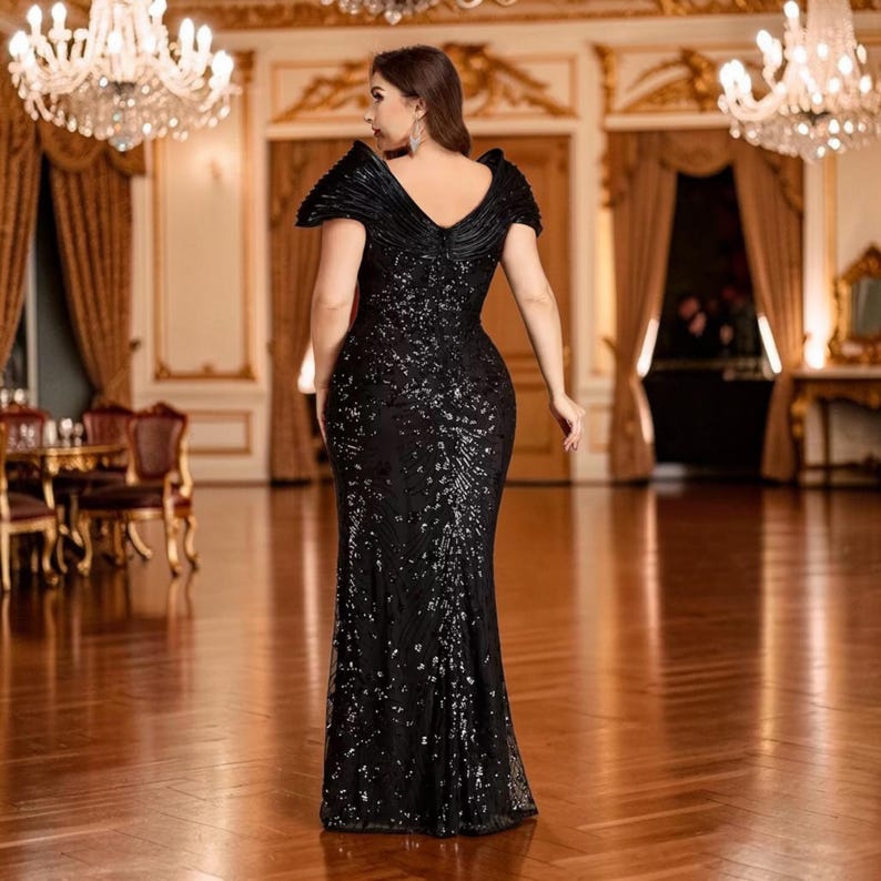 K&ouml;nnte beinhalten: Ein schwarzes Pailletten-Abendkleid mit V-Ausschnitt und kurzen &Auml;rmeln. Das Kleid hat ein figurbetontes Oberteil und einen bodenlangen Rock. Das Kleid wird in einem gro&szlig;en Ballsaal mit Kronleuchtern und goldenen Akzenten getragen.