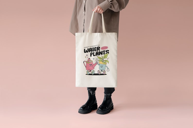 May include: A white tote bag with a cartoon watering can and potted plant design. The text on the bag reads "Don't forget to water your plants".