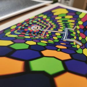 Puede incluir: Una impresi&oacute;n colorida que presenta una figura estilizada flotando sobre un patr&oacute;n hexagonal. La obra de arte utiliza una paleta vibrante de azules, verdes, amarillos, naranjas y morados. La figura tiene una cara sonriente y un contorno plateado.
