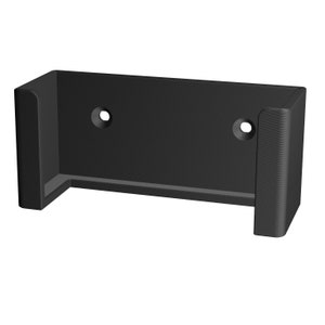 May include: Black plastic wall mount with two holes for screws. The mount has a rectangular shape with a curved opening on one side.