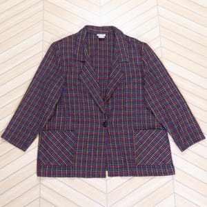May include: A multi-colored plaid blazer with a single-button closure and two front pockets. The blazer features a classic notched lapel and is made of a woven fabric. The plaid pattern includes red, yellow, green, and blue hues.