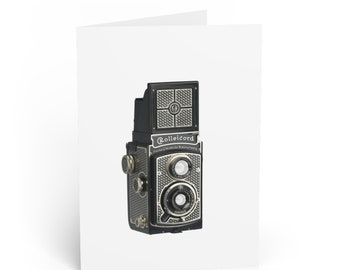 Pode incluir: Uma câmera Rolleicord preta e prateada com um design texturizado. A câmera tem duas lentes e um visor na parte superior.