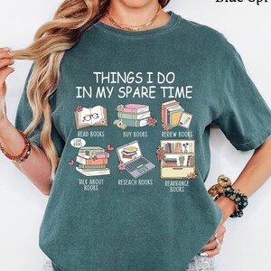 May include: A teal-colored t-shirt with the text "THINGS I DO IN MY SPARE TIME" and illustrations of books. The shirt also features the phrases "READ BOOKS", "BUY BOOKS", "REVIEW BOOKS", "TALK ABOUT BOOKS", "RESEARCH BOOKS", and "REARRANGE BOOKS".