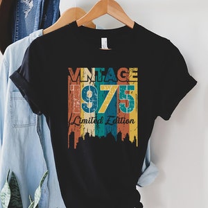 May include: Black t-shirt with a vintage-style graphic that says "Vintage 1975 Limited Edition" in colorful, faded lettering.