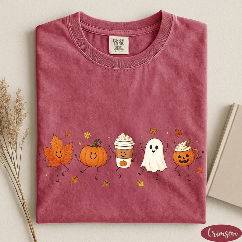 K&ouml;nnte beinhalten: Ein karmesinrotes Kurzarm-T-Shirt mit einem Grafikdruck eines l&auml;chelnden Ahornblatts, eines K&uuml;rbisses, eines Kaffeebechers, eines Geistes und einer Halloween-Laterne, die alle mit Armen und Beinen dargestellt sind.