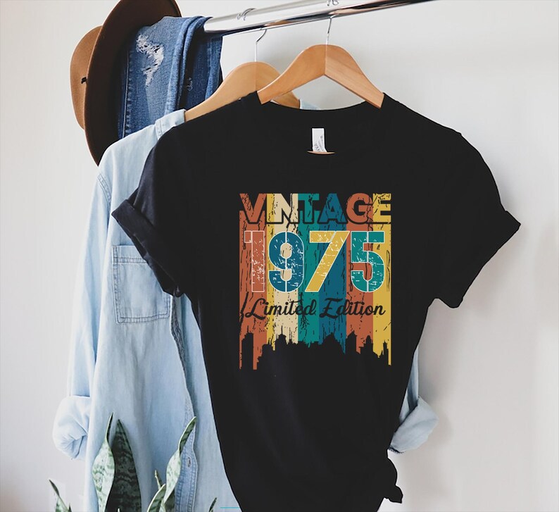 May include: Black t-shirt with a vintage-style graphic that says "Vintage 1975 Limited Edition" in colorful, faded lettering.