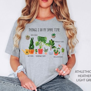 May include: Light grey t-shirt with the text "THINGS I DO MY SPARE TIME" and illustrations of plants. The shirt also has the text "ATHLETHICH HEATHER LIGHT GREY" on the right side.